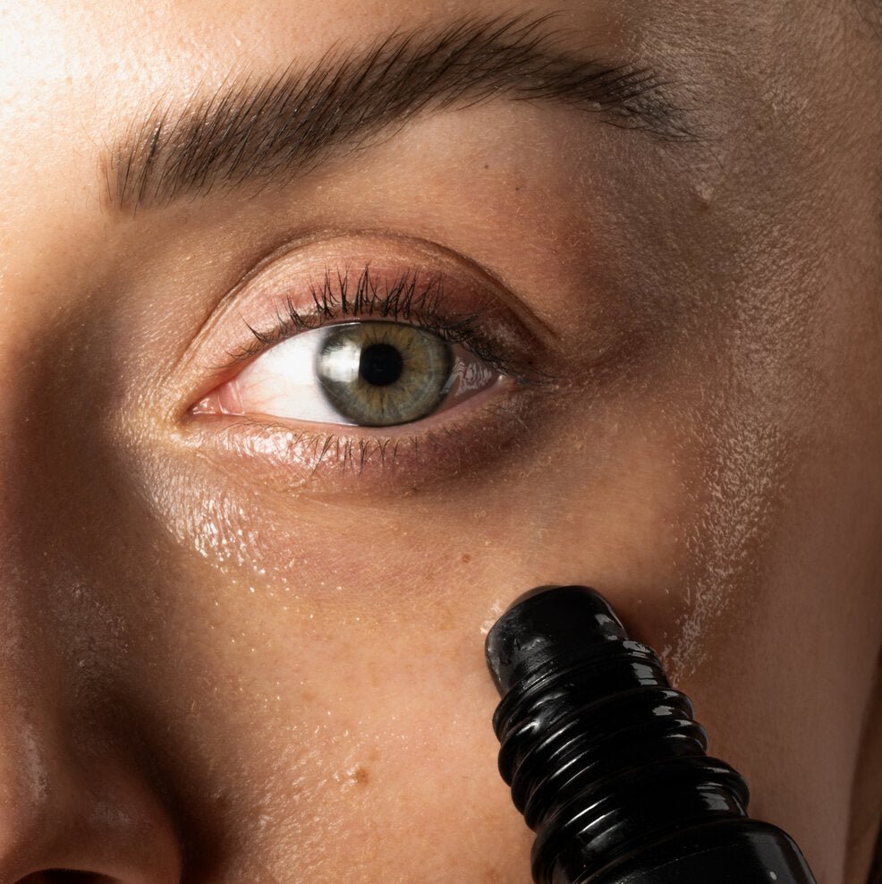 Anwendung des kühlenden Augenserums gegen Augenringe mit Roll-on-Applikator unter dem Auge auf empfindlicher Haut.